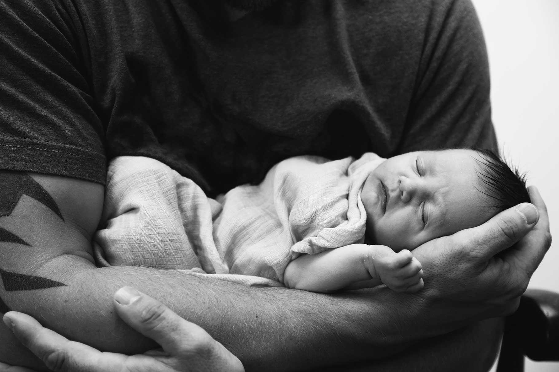 image of baby asleep in fathers arms