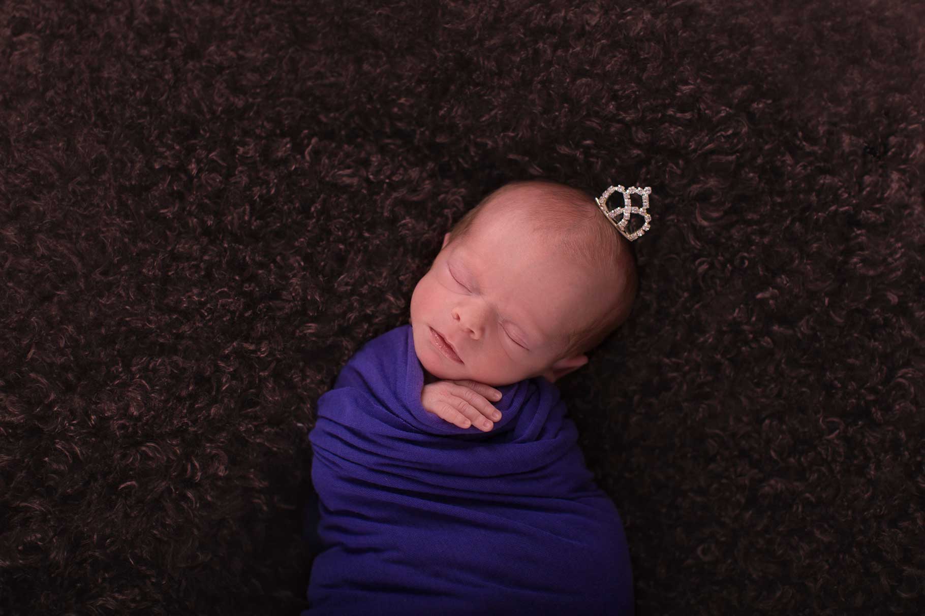 Image of baby swaddled with her hand sticking out