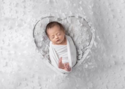 Newborn baby sleeping in heart bowl during newborn session