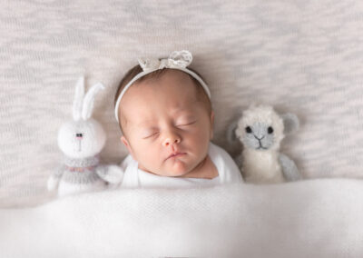 Baby girl cuddling with bunny and lamb stuffies