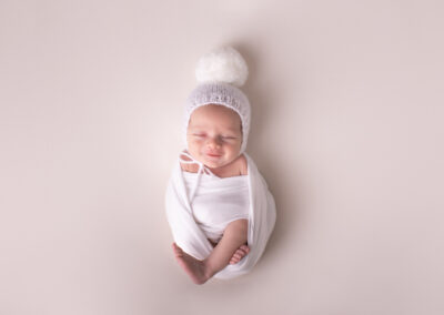 Newborn baby wearing hat with big pom pom