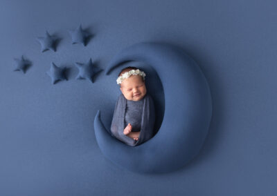 Newborn baby girl posed on moon prop for newborn session