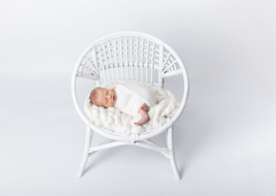 Newborn baby posed on a chair on a white backdrop