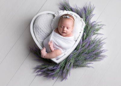 Baby laying in heart bowl surrounded by lavender