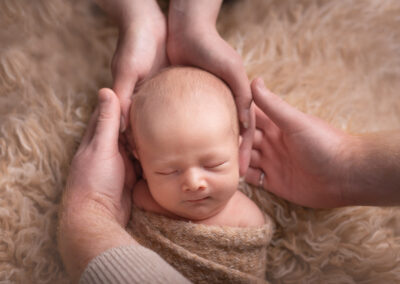 Newborn baby head being held by his parents hands