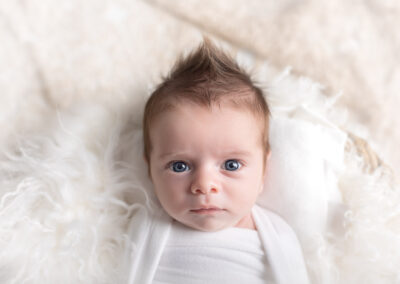Newborn baby with big blue eyes looking at the camera