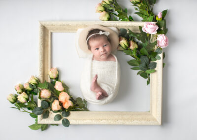 Newborn baby posed with frame prop with roses