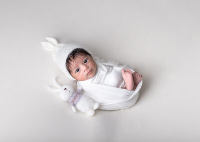Baby dressed as a bunny with a bunny stuffie