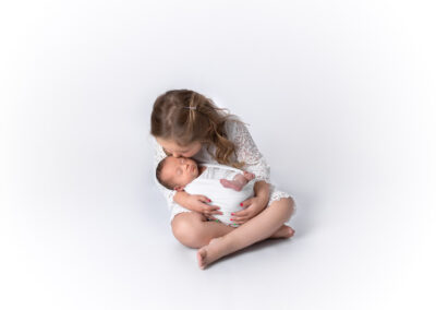 Girl holding her newborn sister in her arms