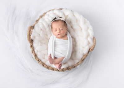 Newborn baby girl wit bow on her head posed for newborn session